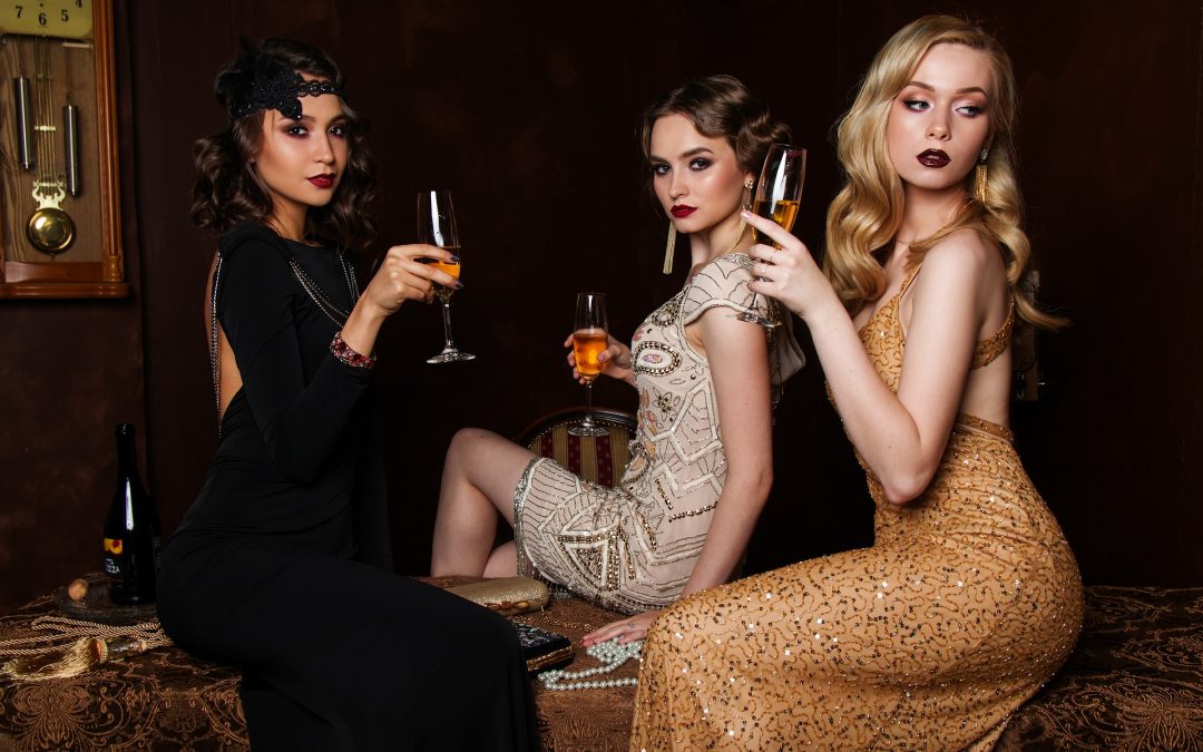 Three beautiful girls in dresses drinking champagne and posing to the picture