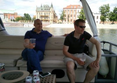 Two friends sitting in a boat drinking beer on a sightseeing tour around Wroclaw, Poland